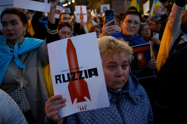 A woman holds a sign with a grahpic of a missile rocket during a rally in front of the Russian Embassy in Warsaw, Poland on 10 October, 2022. S