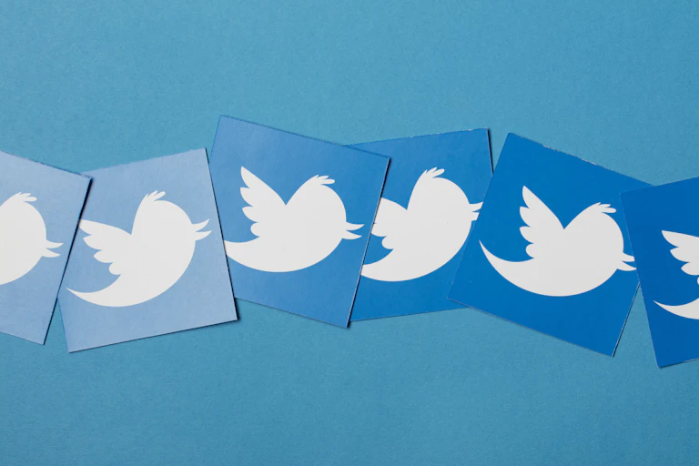 a row of square cards of varying shades of blue, each one showing the twitter logo, a white silhouette of a cartoon bird