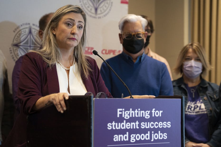 A woman is seen at a podium speaking.