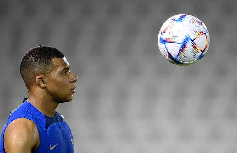 A soccer player looks at a ball in the air.