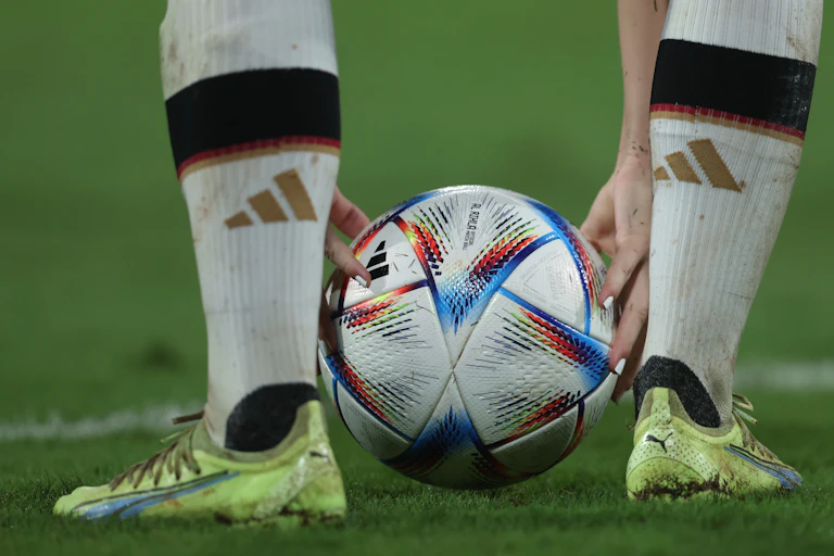 A soccer player putting a ball on the grass.