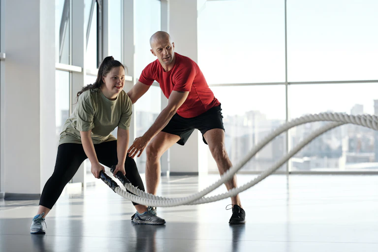 A woman and man exercise in a gym.