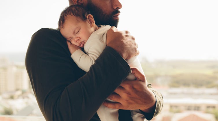 A man snuggles an infant.