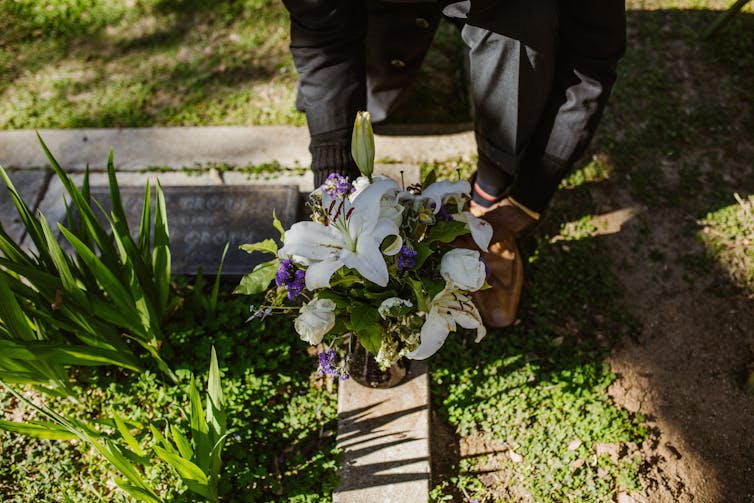 person puts flowers on grave