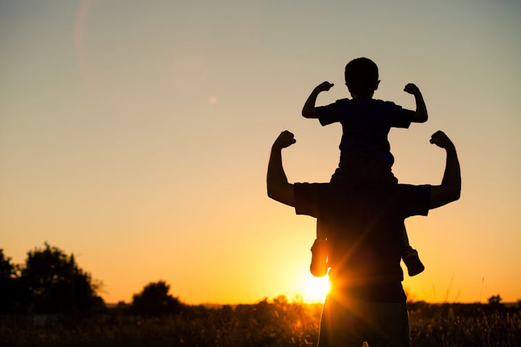 A father and son are set against a sunset background.