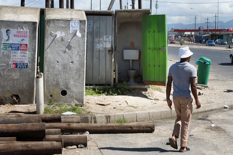 Man walking past public toilet with the door open