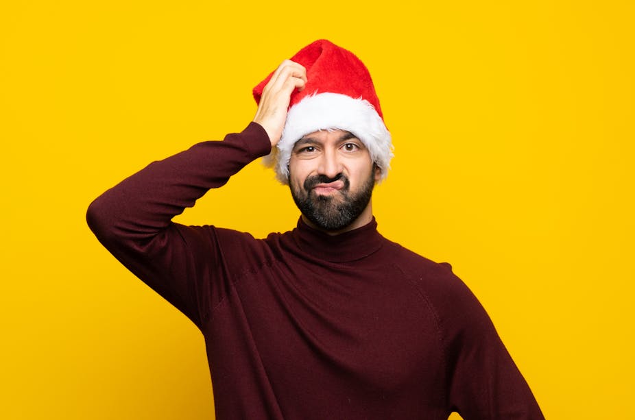 Man with Christmas hat over isolated yellow background with an expression of frustration and not understanding