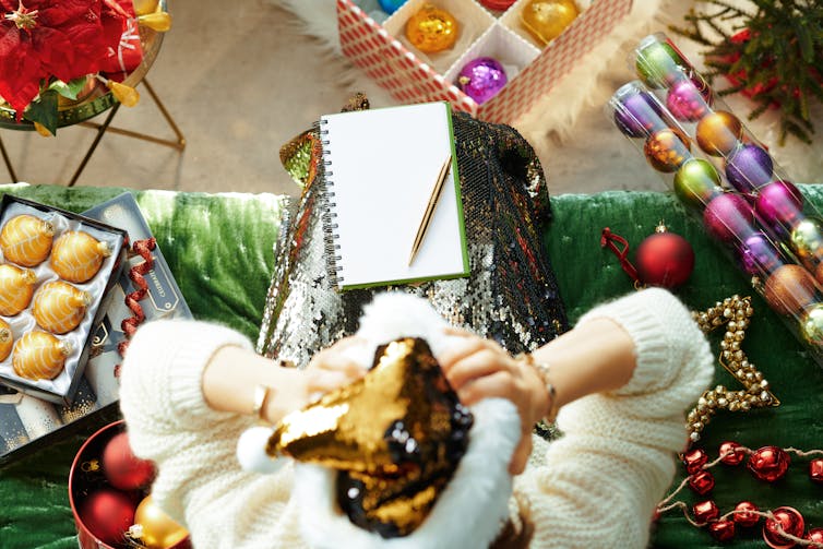 Upper view of stressed stylish housewife in sparkle gold sequin santa hat sitting on sofa in the modern living room at Christmas