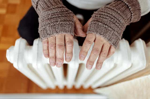 Hands with gloves over a radiator.