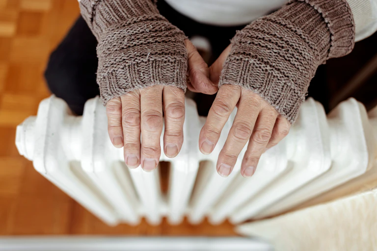 Hands with gloves over a radiator.