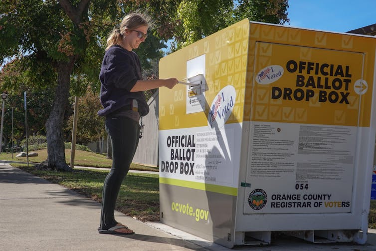 A woman places her ballot in a drop box during the US midterms.