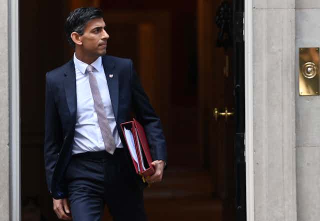 Rishi Sunak leaving Downing Street with two red folders.