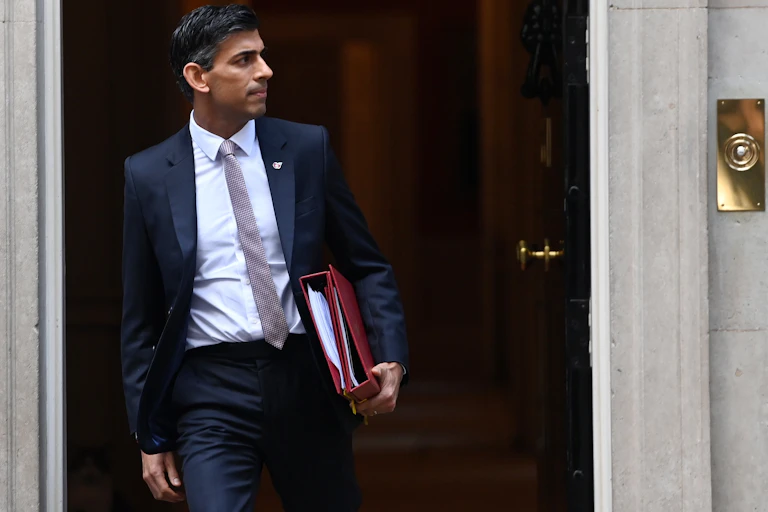 Rishi Sunak leaving Downing Street with two red folders.
