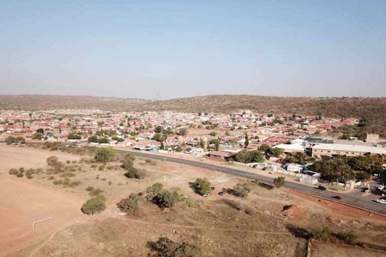 Houses surrounded by open space, vegetation and hills.