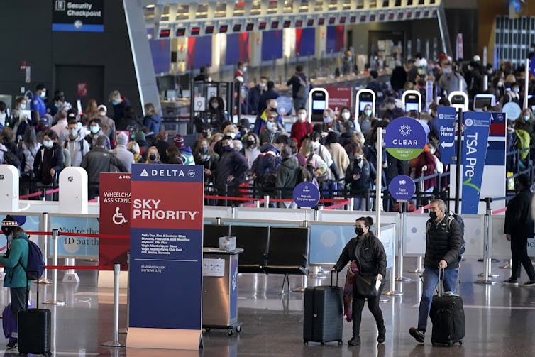 many people wait in lines at a security checkpoint at an airport