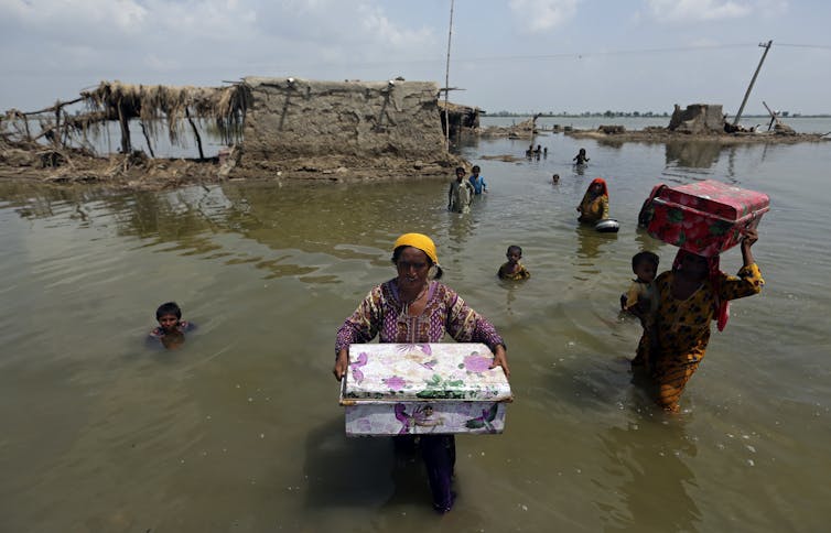 People in Pakistan carry belongings through flood waters