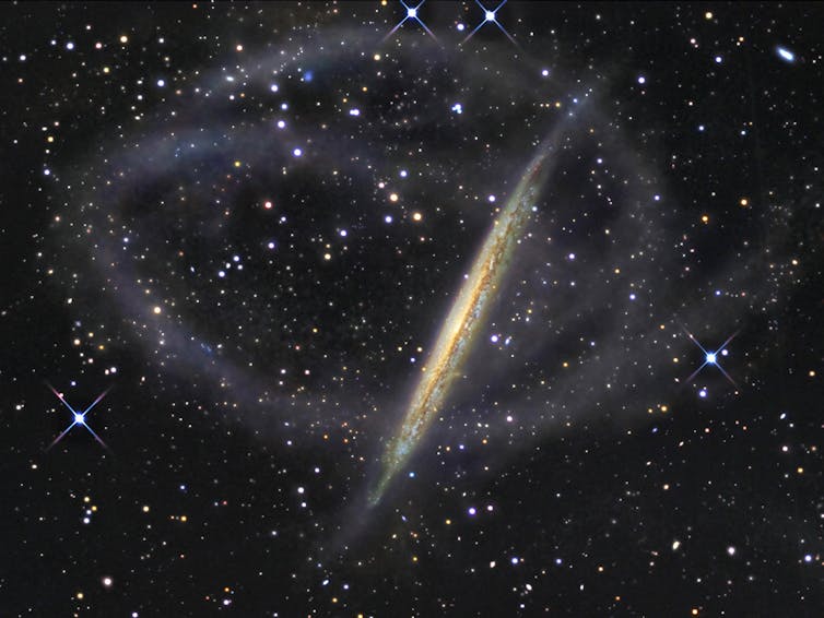 Immagine di NGC 5907, una galassia che ospita deboli flussi di stelle che la avvolgono tutt'intorno.