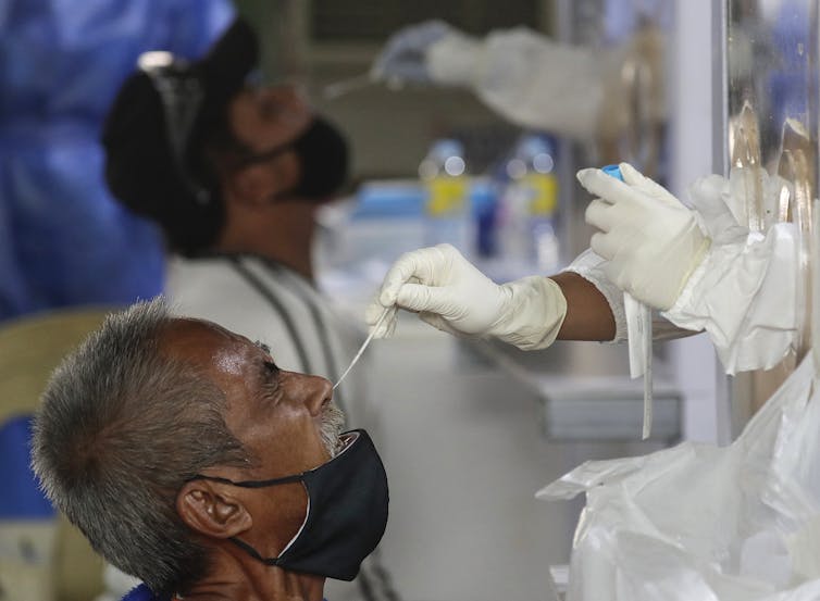 mass testing site for covid. Two men sit for nasal swab
