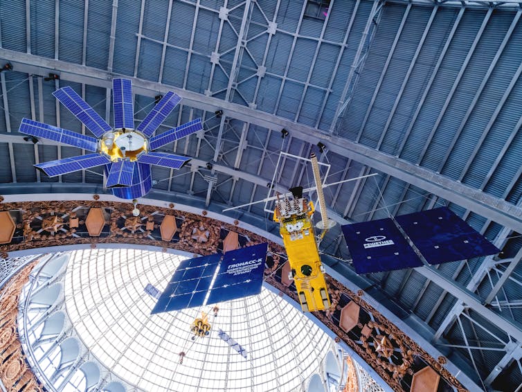 Satellites GLONASS and Geo-IK displayed overhead at an exhibit in Moscow.