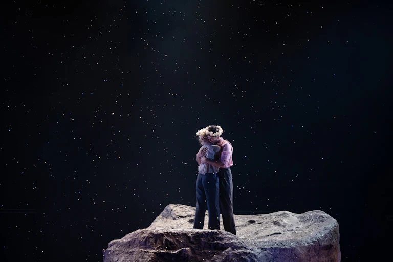 Two people embrace on stage