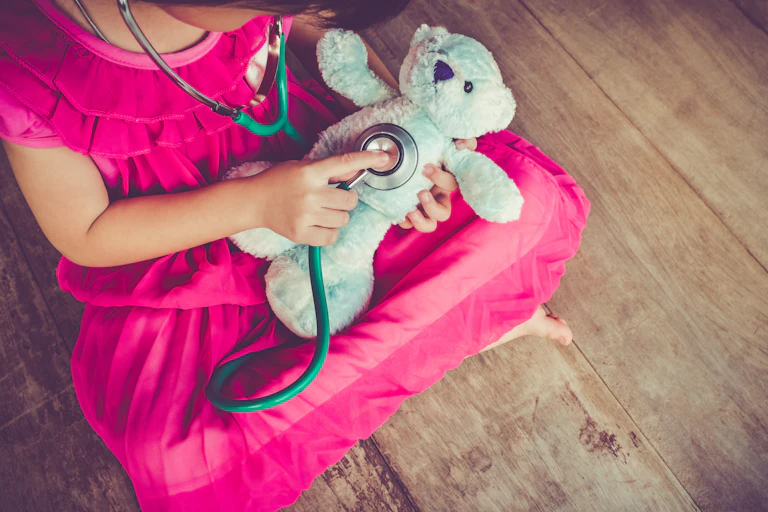 Girl playing with teddy bear and stethoscope