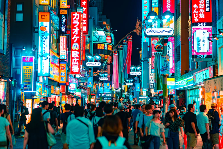 A busy shopping district lit in teal and red lights
