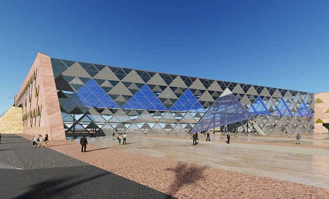 An exterior photograph of the Grand Egyptian Museum against blue skies. The building has mirrored triangular glass covering its exterior, mirroring Egypt's famous pyramids