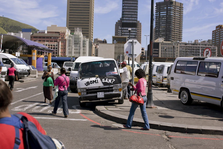 people walking past minibus taxis