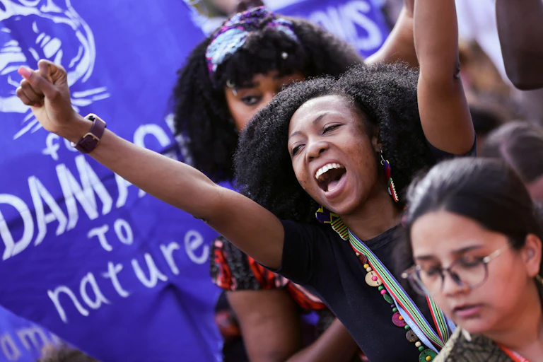 women protesting in front of purple banner