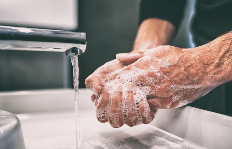 Hands being washed under a tap.