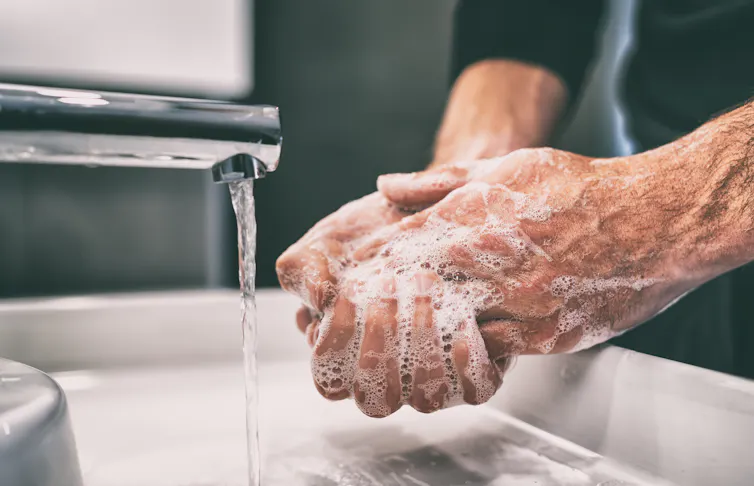 Hands being washed under a tap.