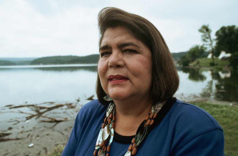 close-up portrait of woman with brown hair cropped to neck and backdrop of water's edge