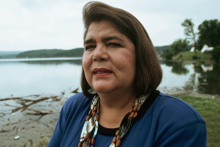 close-up portrait of woman with brown hair cropped to neck and backdrop of water's edge