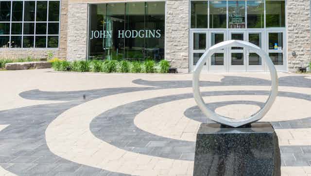 A large sculpture of a ring in front of a university building.