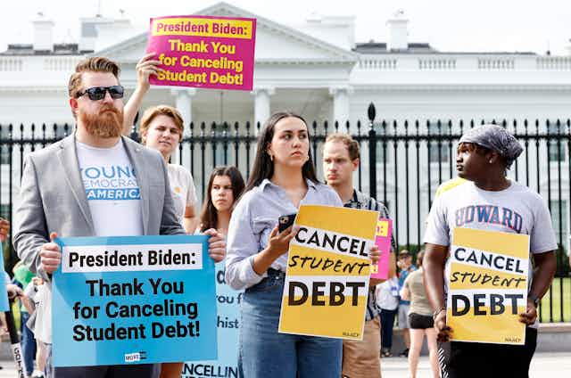 People hold signs in front of the White House that state "Cnacel Student Debt."