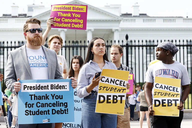 People hold signs in front of the White House that state "Cnacel Student Debt."