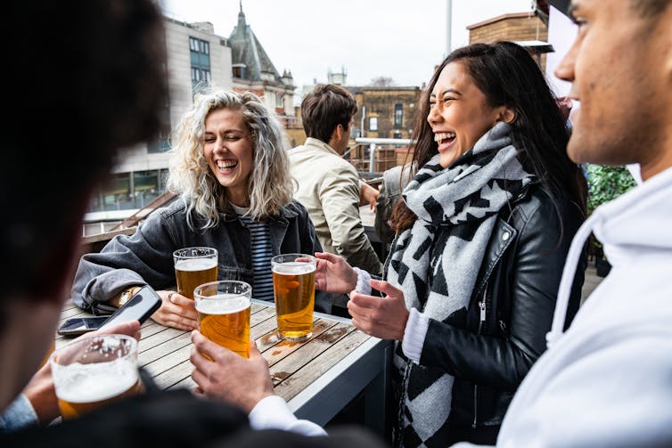 A group of young people having beers outside.