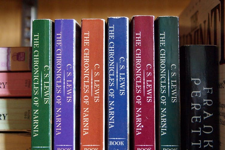 Narnia books sit upon a shelf.