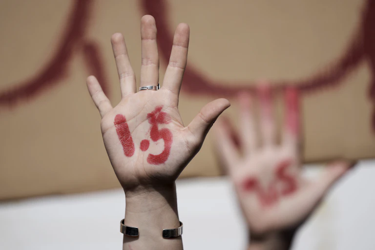 2 protesters' raised hands painted with 1.5 during COP27