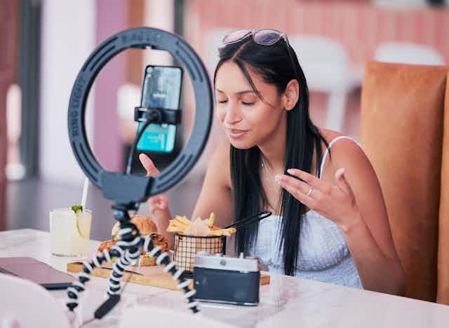 A woman eats food while videoing herself.