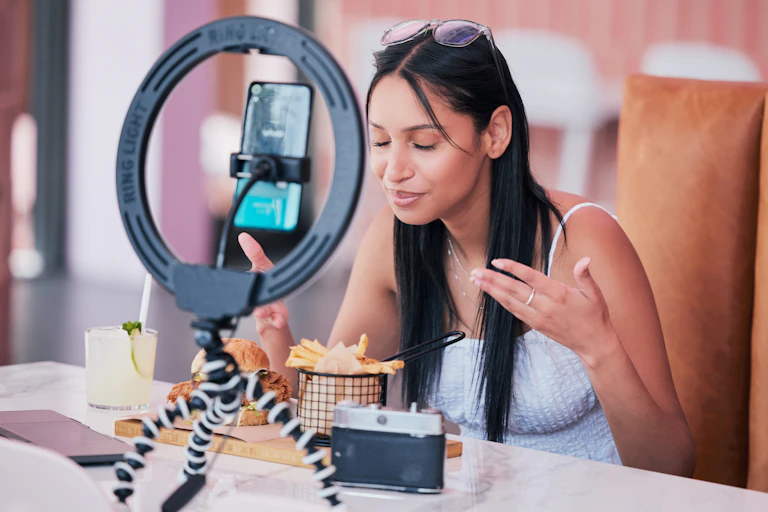 A woman eats food while videoing herself.