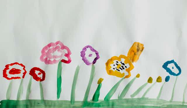 A child's painting of colourful flowers on green grass.