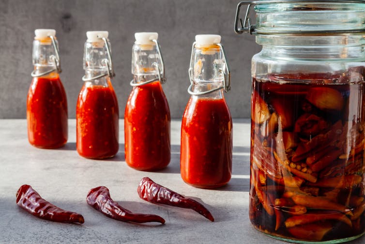 chillis in jars, on table, in sauce