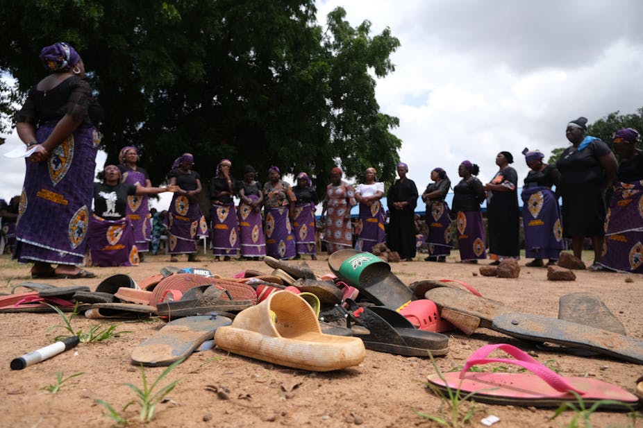 Women standing round sandals on the ground.