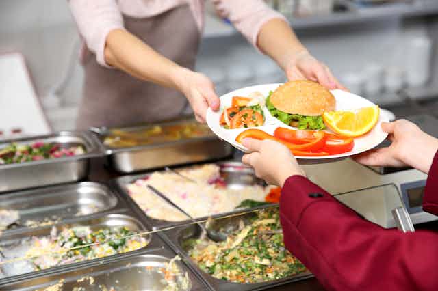 Catering staff handing plate of food to child