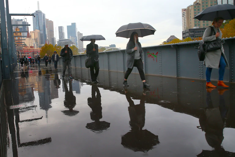 people in city walk through water with umbrellas