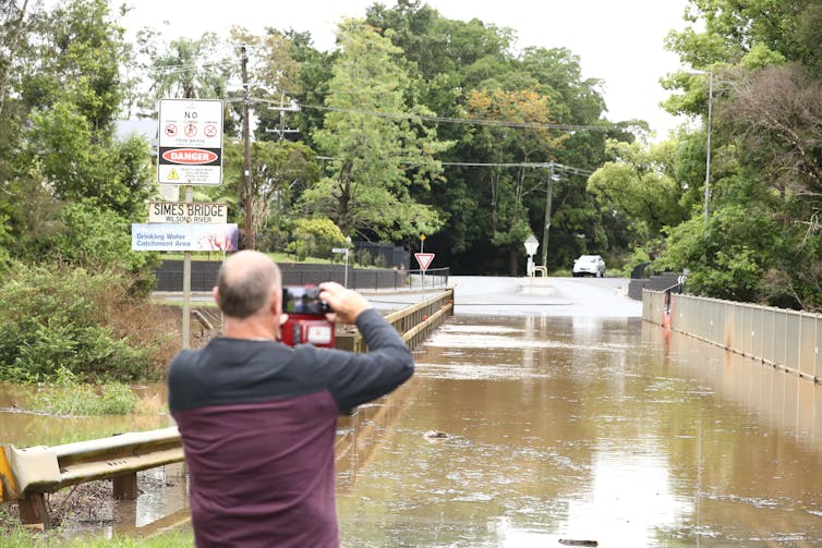 man photographs flooded road