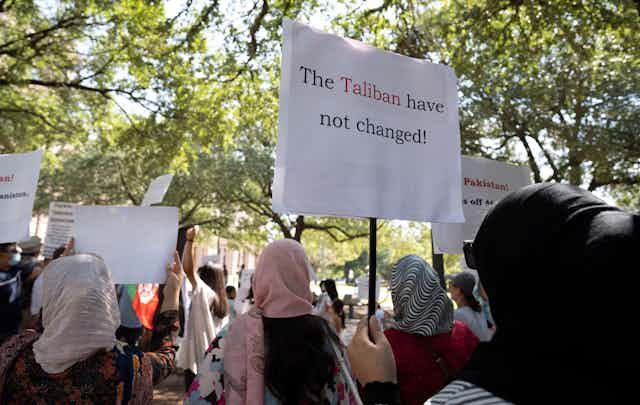 Women in traditional Afghan dress hold up banners in protest at the Taliban's treatment of women in Afghanistan.