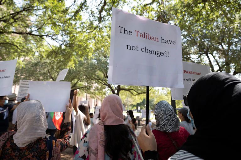 Women in traditional Afghan dress hold up banners in protest at the Taliban's treatment of women in Afghanistan.