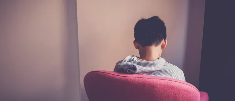 a young person sitting in a red chair with their back to the viewer